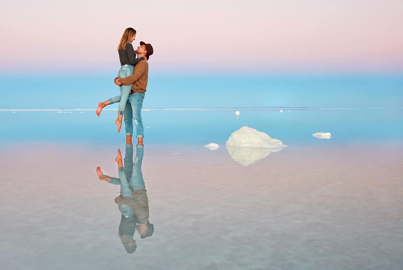 Couple reflected in the Uyuni waters at twilight